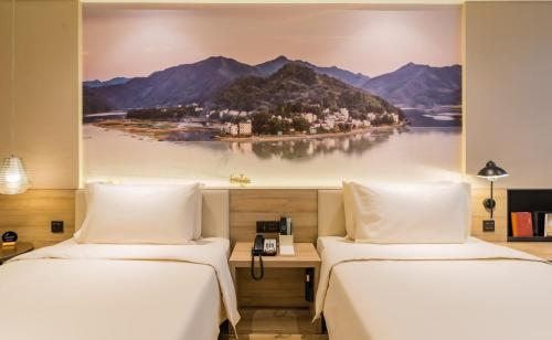 合肥合肥南站滨湖会展中心亚朵酒店的两张位于酒店客房的床,墙上挂着一幅画