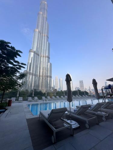 迪拜Luxury 3-bedroom apartment with a stunning view of the Burj Khalifa and the Fountain的一座带躺椅的游泳池以及两座高楼