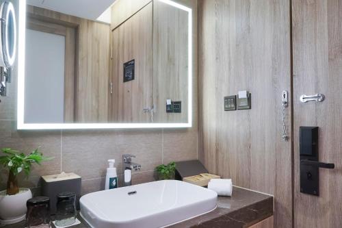 哈尔滨哈尔滨松北冰雪大世界亚朵酒店的浴室设有白色水槽和镜子