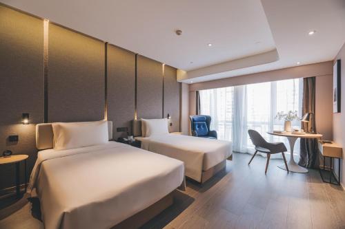 上海上海徐家汇天钥桥亚朵S酒店的酒店客房设有两张床和一张桌子。