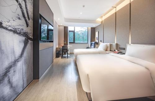 昆明昆明翠湖亚朵酒店的酒店客房设有两张床和一张桌子。