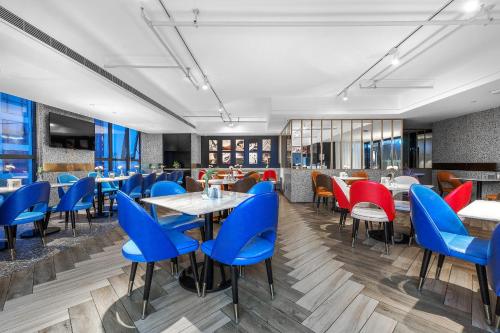 成都成都九眼桥亚朵网易严选酒店的餐厅设有蓝色和红色的椅子和桌子