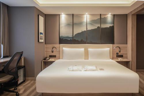 烟台烟台金沙滩亚朵酒店的卧室配有一张白色大床和一张书桌