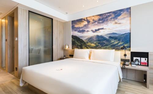 厦门厦门集美大学亚朵酒店的卧室配有一张白色大床,墙上挂有绘画作品