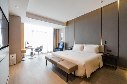 无锡无锡海岸城亚朵酒店的酒店客房设有一张大床和一张桌子。