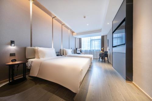 南昌南昌西站国际博览城亚朵酒店的酒店客房设有一张白色大床和一张书桌