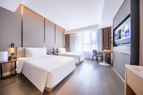乌鲁木齐乌鲁木齐机场德港万达亚朵酒店的酒店客房设有一张白色大床和一张书桌