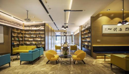 杭州杭州萧山人民广场亚朵酒店的图书馆配有黄色和蓝色的椅子和桌子