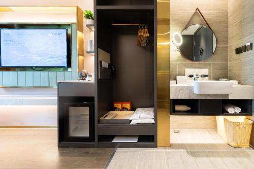 深圳深圳南山深圳湾亚朵轻居酒店的一间带水槽的浴室和墙上的电视