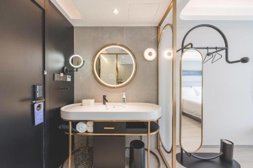 杭州杭州下沙轻居酒店的一间带水槽和镜子的浴室以及一张床