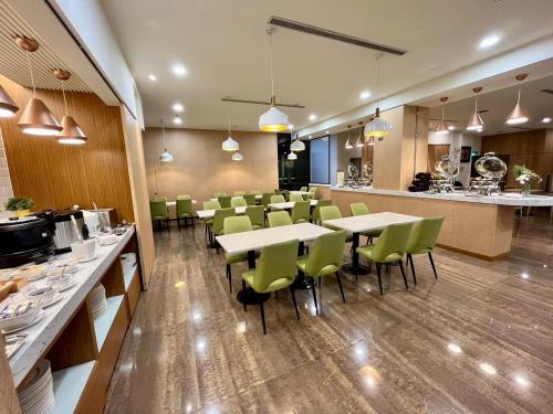 台南台南圣旺商旅的一间带桌子和绿色椅子的餐厅以及一间厨房