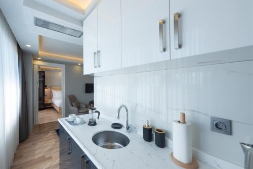 伊斯坦布尔Art Karaköy Suites的一间带水槽的白色厨房和一个房间