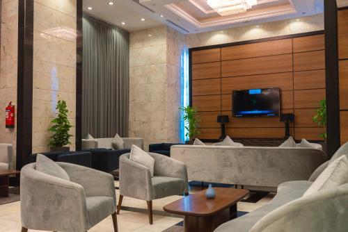 麦地那La Cordia Hotel Apartment的一间配有沙发的等候室和墙上的电视