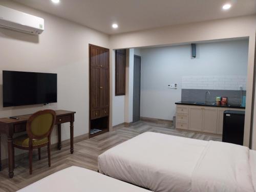 Phú MỹAn Nhiên Villa Hotel的一间卧室配有一张床、一张书桌和一台电视