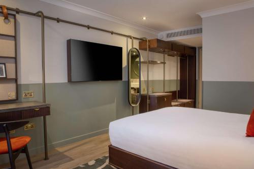 圣奥尔本斯The Samuel Ryder Hotel St Albans, Tapestry Collection Hilton的一间卧室配有一张床和一台平面电视