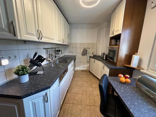 萨格勒布Maksimirhouse的厨房配有白色橱柜和黑色台面