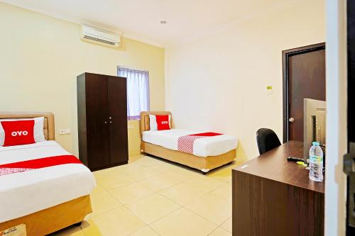 DaresOYO Flagship 91290 Pondok Inap Shofwa 2的酒店客房配有两张床和一张书桌