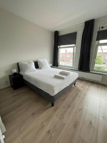 海牙Cosy Apartment in the Hague!的一间卧室配有一张铺有木地板的白色床单。