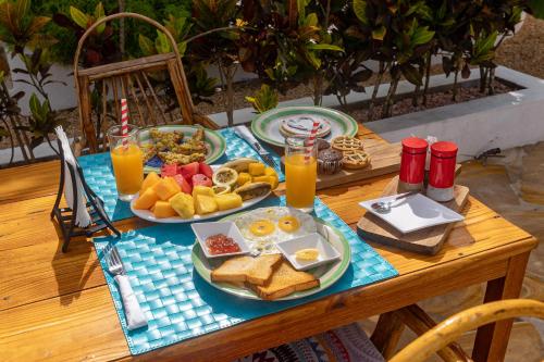 南威Cactus lodge Zanzibar的餐桌上摆放着早餐食品和橙汁盘