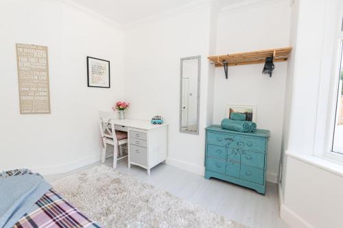 伯恩茅斯Modern flat, sleeps 4, close to beach,Parking,WiFi - Queens Park Views的一间卧室配有书桌和一张蓝色橱柜的床。