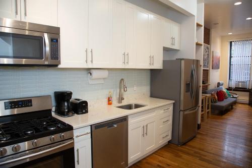 纽约The Harlem Cascades的厨房配有白色橱柜和不锈钢用具