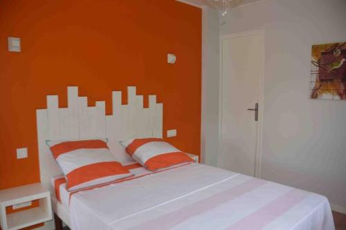 Rivière-Pilotekaï colibri的一间卧室配有一张白色的床和橙色的墙壁