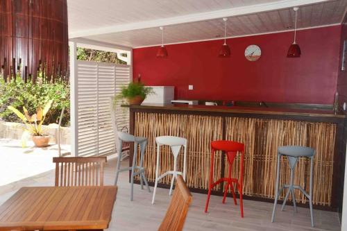 Rivière-Pilotekaï colibri的厨房设有红色墙壁和凳子的酒吧
