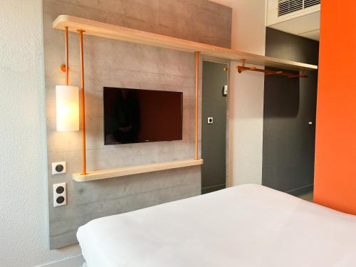 Saint-Christol-lès-Alès圣克里斯托尔莱萨勒宜必思快捷酒店的一间卧室配有一张床,墙上配有电视