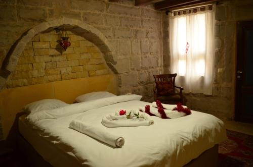 阿瓦诺斯Mozaik Stone Hotel的一张铺有白色床单和红色鲜花的床