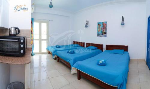 达哈布Dolphina hotel & Restaurant的一间设有四张蓝色床铺和电视的客房