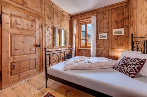CastasegnaIn val Bregaglia mille possibilità di benessere的一间卧室配有一张带木墙和窗户的床。