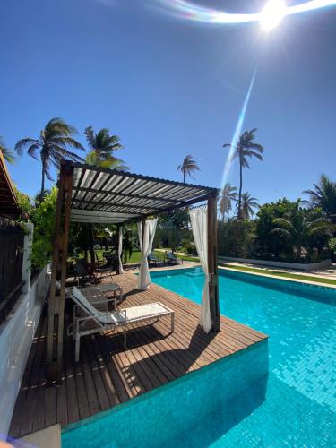 瓜吉鲁BEACH VILLA Camurupim的游泳池旁带凉棚和椅子的游泳池