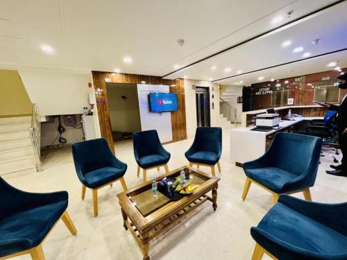 新德里Hotel Apple Inn n Suites, New Delhi的客厅配有蓝色椅子和茶几