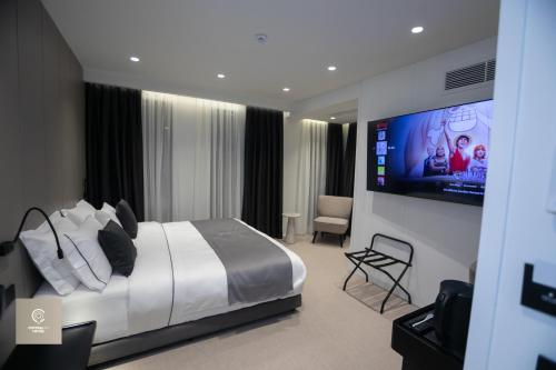 地拉那Central Inn Hotel的一间卧室配有一张床和一台平面电视