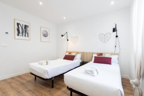 帕伦西亚INSIDEHOME Apartments - La Casita de Irene的配有白色墙壁和木地板的客房内的两张床