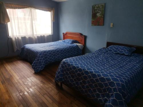 昆卡La Muralla的一间卧室设有两张床和窗户。