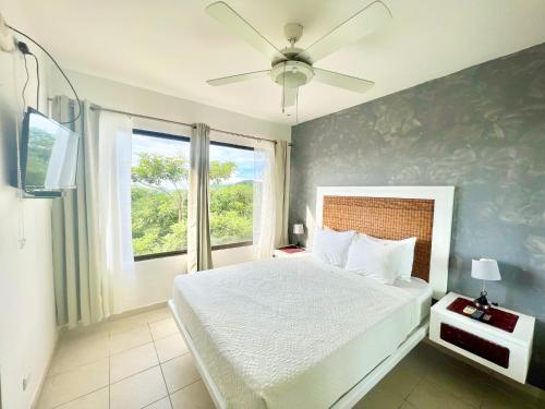 科克Tropical Gardens Suites and Apartments的一间卧室配有一张带吊扇和窗户的床。