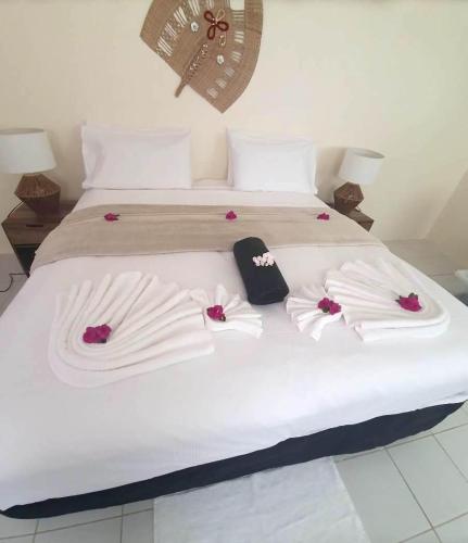 UtungakeWolfgramm Beachfront Motel的一张床上有白色床单和粉红色的鲜花
