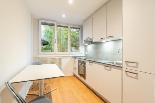 伯尔尼Möblierte Zimmer - gratis Parkplatz的厨房配有白色橱柜、桌子和窗户。