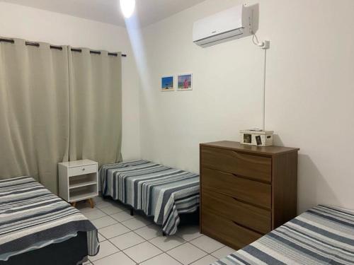 瓜鲁雅Apartamento aconchegante - Enseada - Guarujá的一间设有两张床的房间和一个梳妆台
