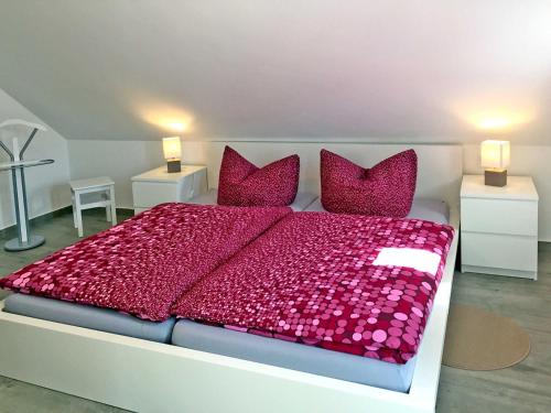 KröslinFerienwohnung Le Papillon的卧室配有一张大床,提供红色床单和枕头