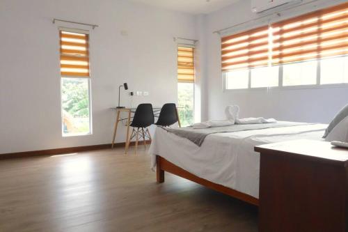 宿务Brand New Home in Cebu City with 3 Large Bedrooms!的一间白色卧室,配有床和2个窗户
