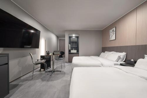 安山市Workers Hotel Ansan by AANK的酒店客房设有两张床和一台平面电视。