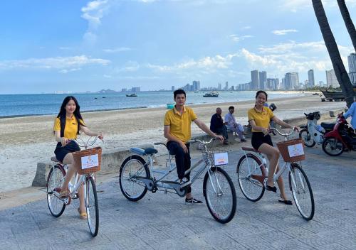 岘港Sontra Sea Hotel的三人骑行在沙滩上