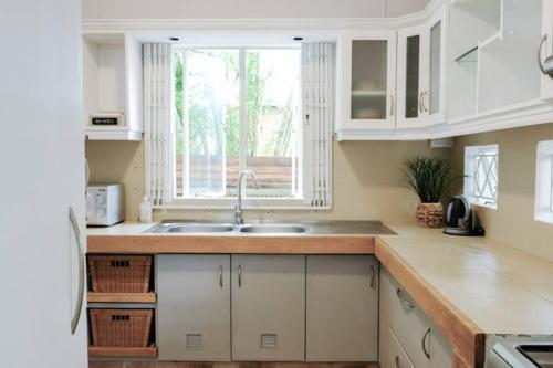 塔马兰Tamarin River Villa的厨房配有白色橱柜、水槽和窗户。