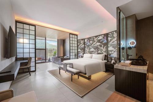 腾冲腾冲暻阁半山温泉酒店的一间带一张床和一张书桌的卧室以及一间浴室。
