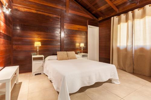 克尤伯厄拉斯Wood House Massaranduba的一间卧室设有木墙和一张铺有白色床单的床。