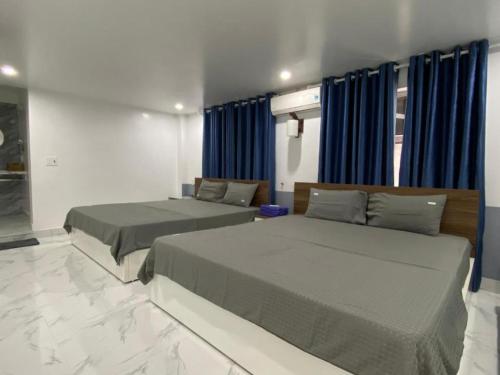 吉婆岛吉婆岛圣托里尼民宿的配有蓝色窗帘的客房内的两张床