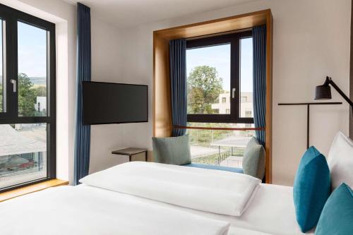 陶努斯山区克龙贝格Vienna House by Wyndham MQ Kronberg的酒店客房设有两张床和窗户。