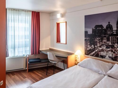 亚琛B&B Hotel Aachen-Hbf的配有一张床和一张书桌的酒店客房